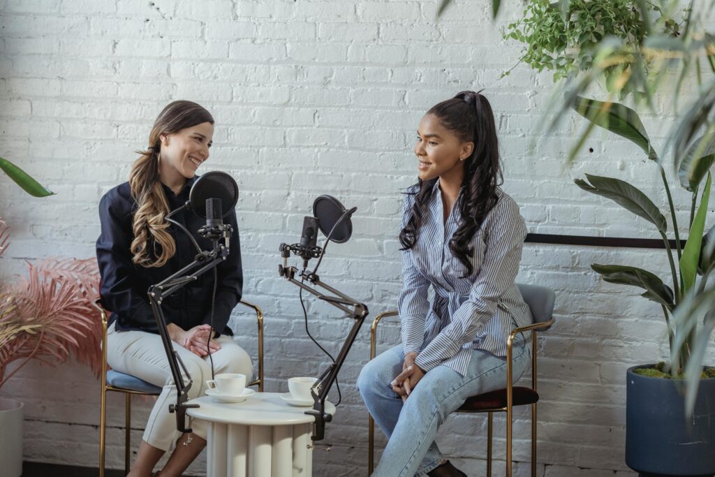 Diverse women communicating while recording voice in studio with white brick walls in daytime